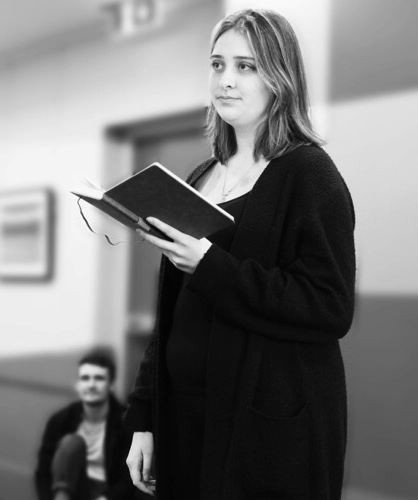 A black and white photo of Alex performing poetry to a crowd